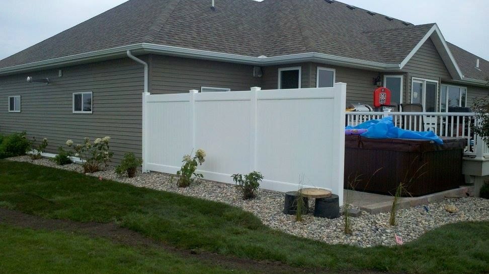 A house with a hot tub behind a white fence.