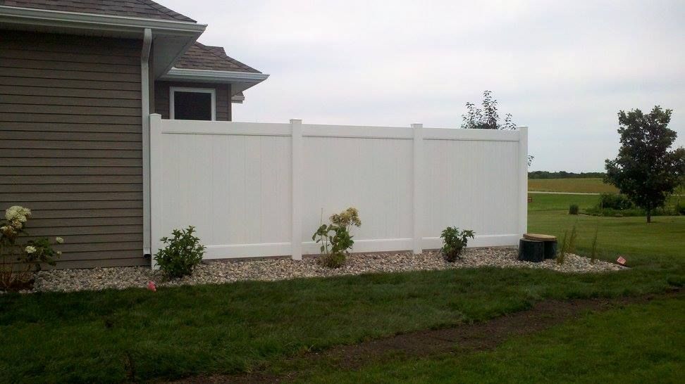 A white fence is in the backyard of a house.