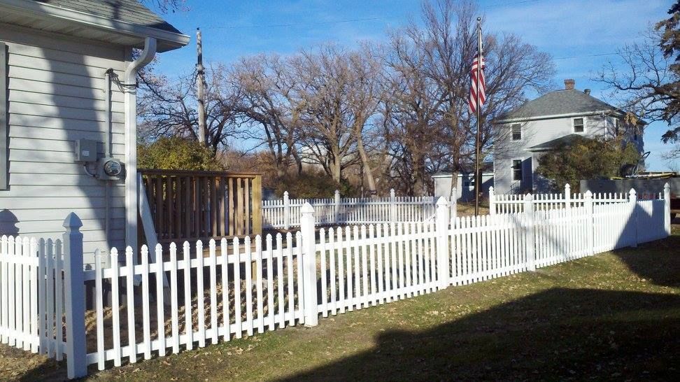 A white picket fence is in front of a house.