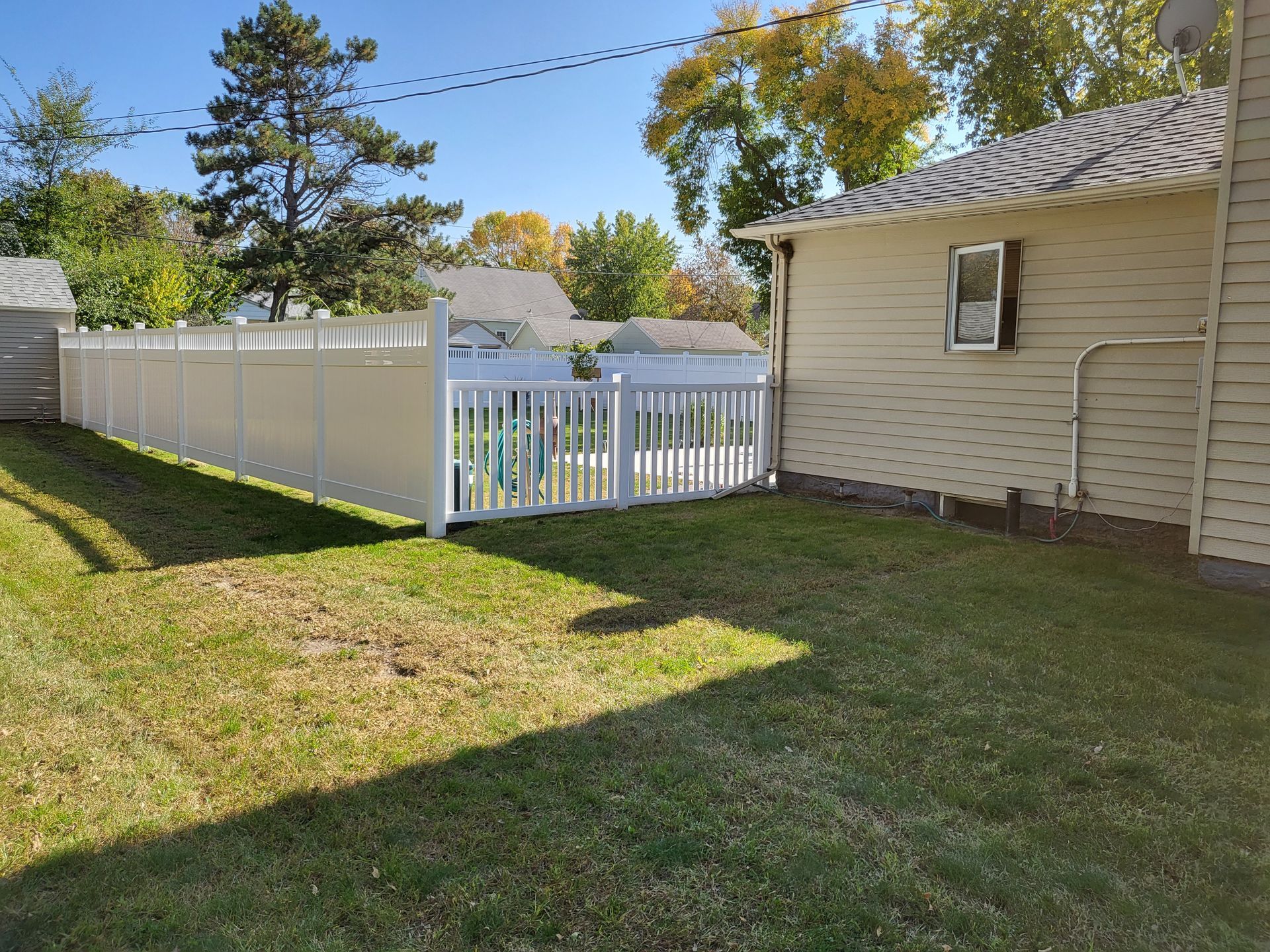 There is a white fence in the backyard of a house.