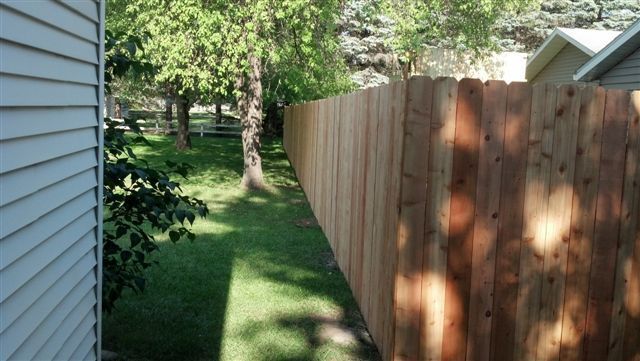 A wooden fence is in the backyard of a house