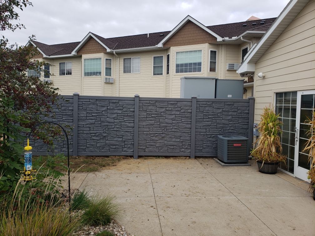 A backyard with a fence and a house in the background.