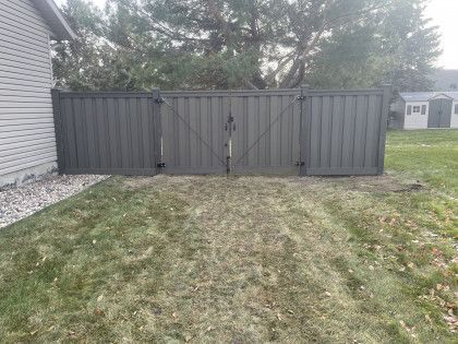 A black fence is in the backyard of a house.