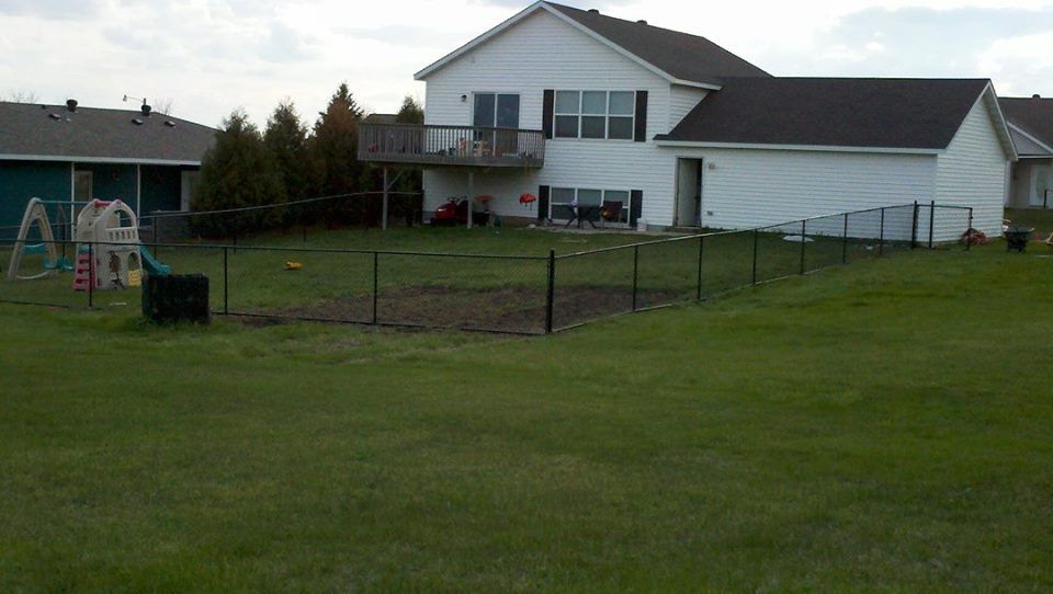 A backyard with a fence and a house in the background