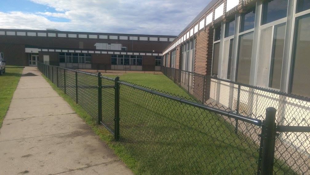 A chain link fence is in front of a school building