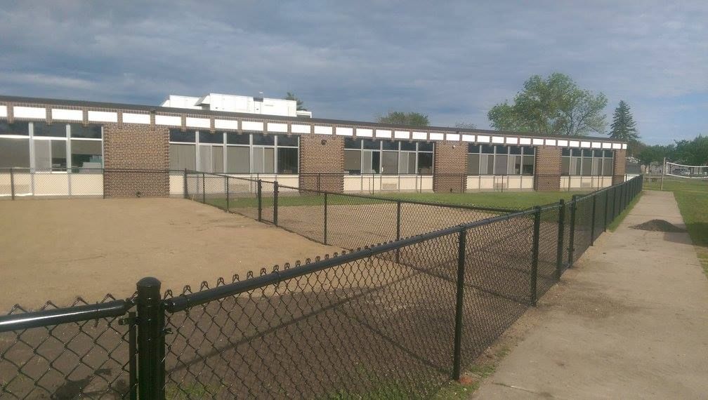 A chain link fence surrounds a brick building
