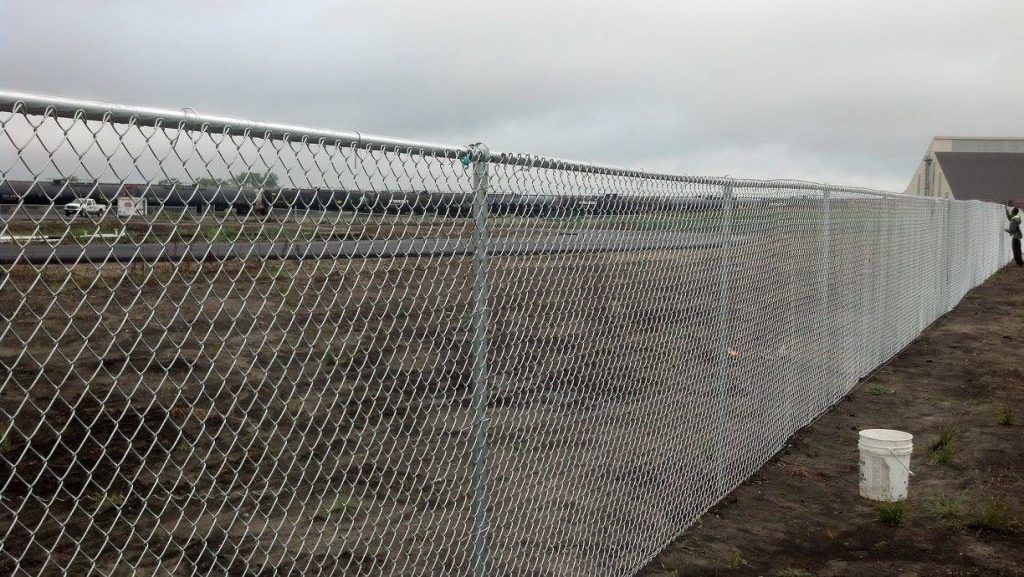 A chain link fence is sitting in the middle of a field.