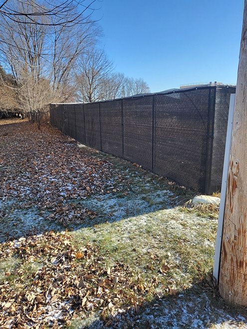 A chain link fence is surrounded by hay bales in a field.