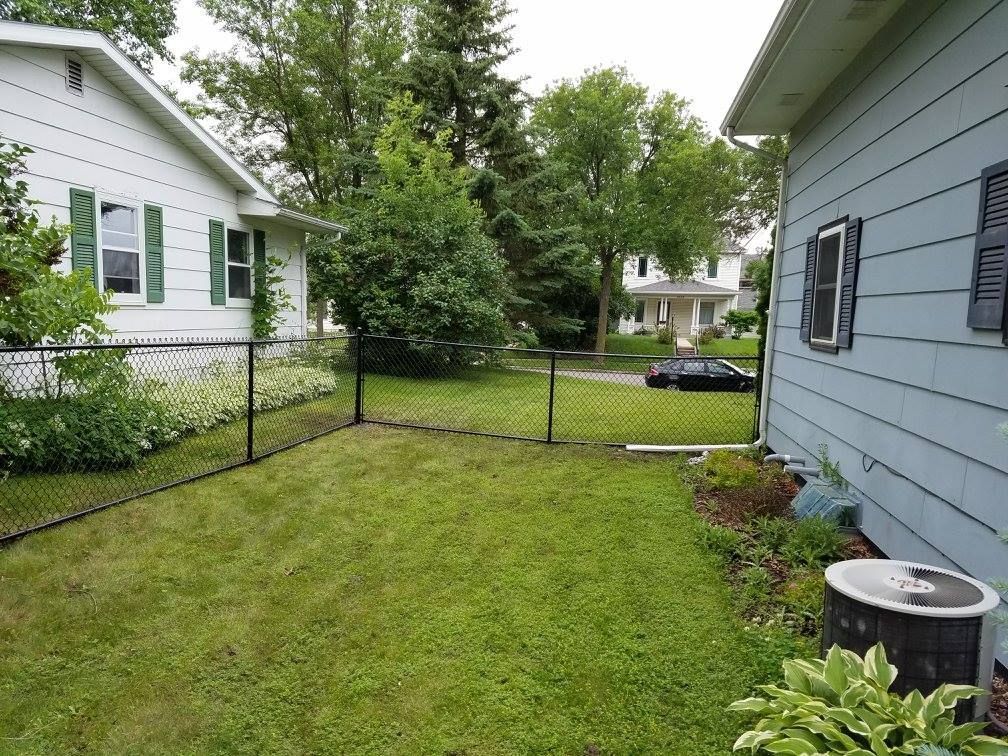 A backyard with a chain link fence between two houses.