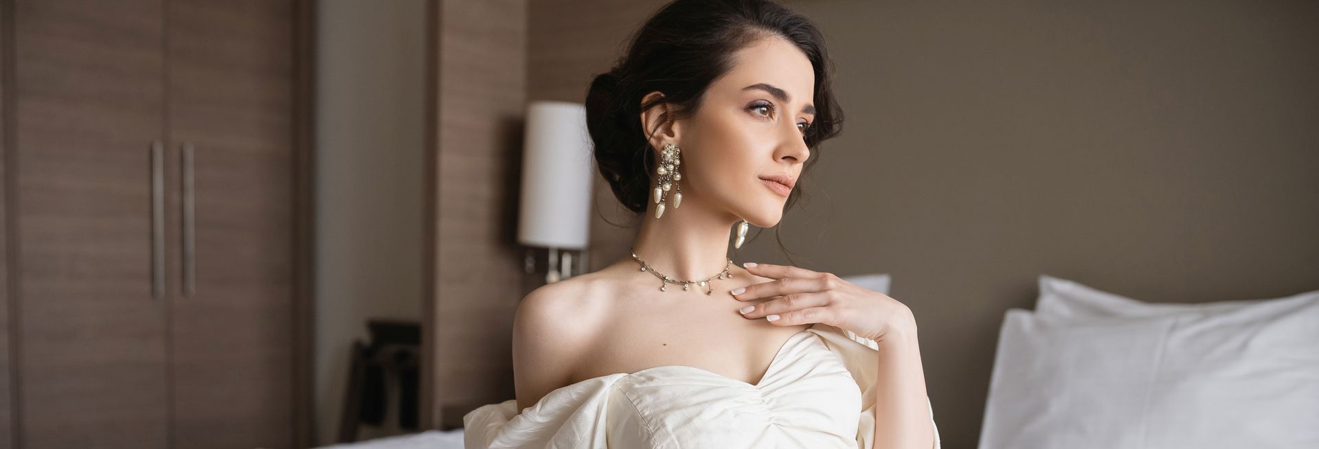 Elegant portrait of a person in formal attire, wearing jewelry, posed indoors.