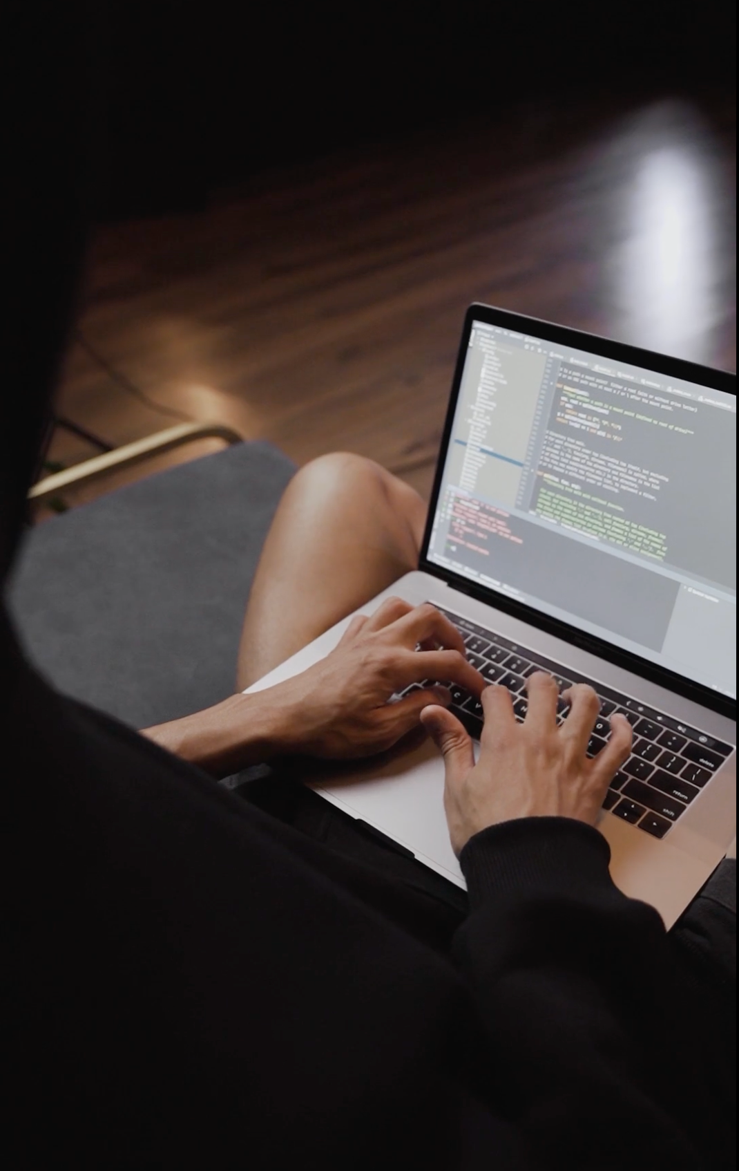 A person is typing on a laptop computer while sitting on the floor.