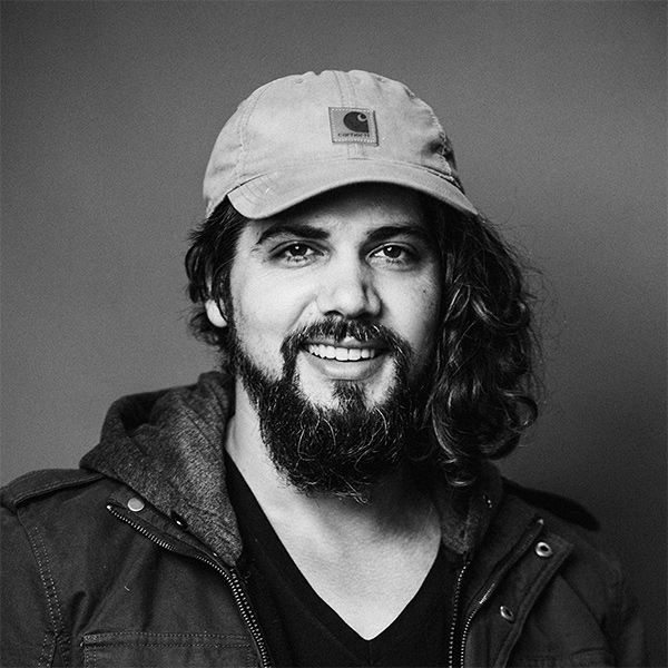 A man with a beard wearing a hat and a jacket