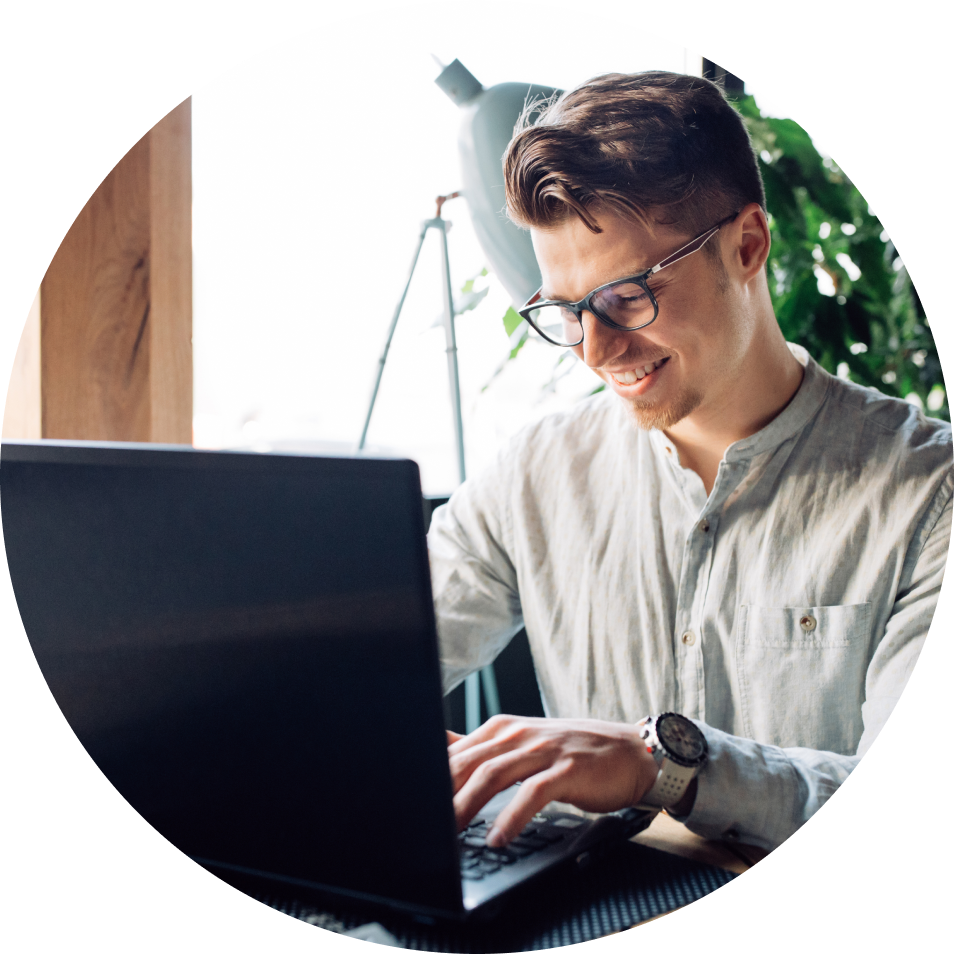 A man wearing glasses is typing on a laptop computer.