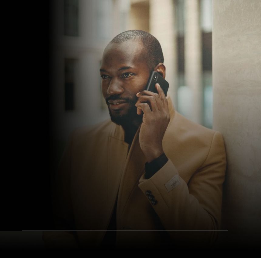 A man leaning against a wall talking on a cell phone