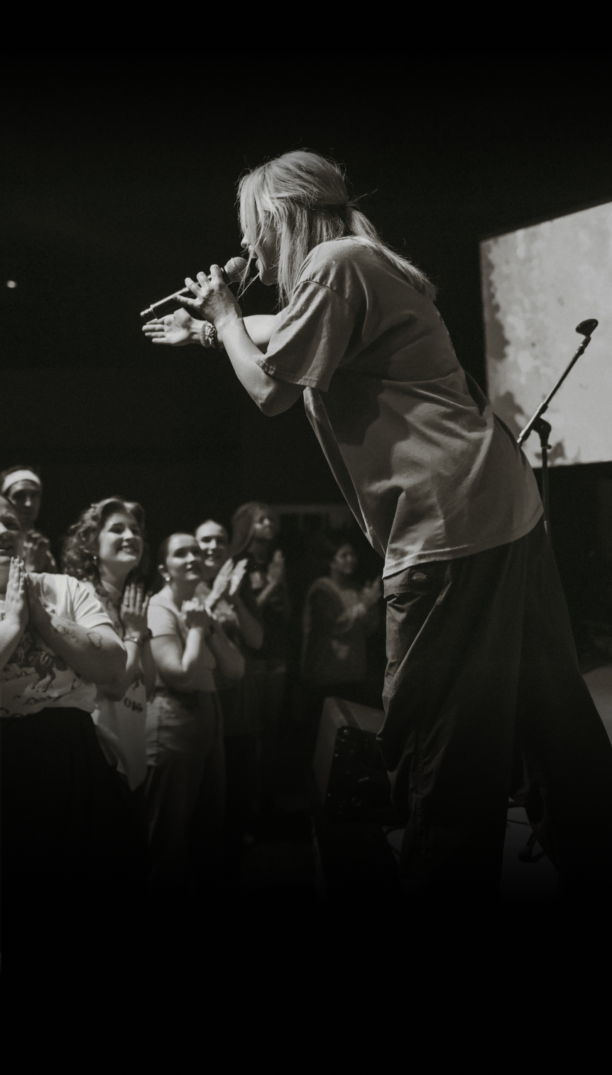 A man is singing into a microphone in front of a crowd.