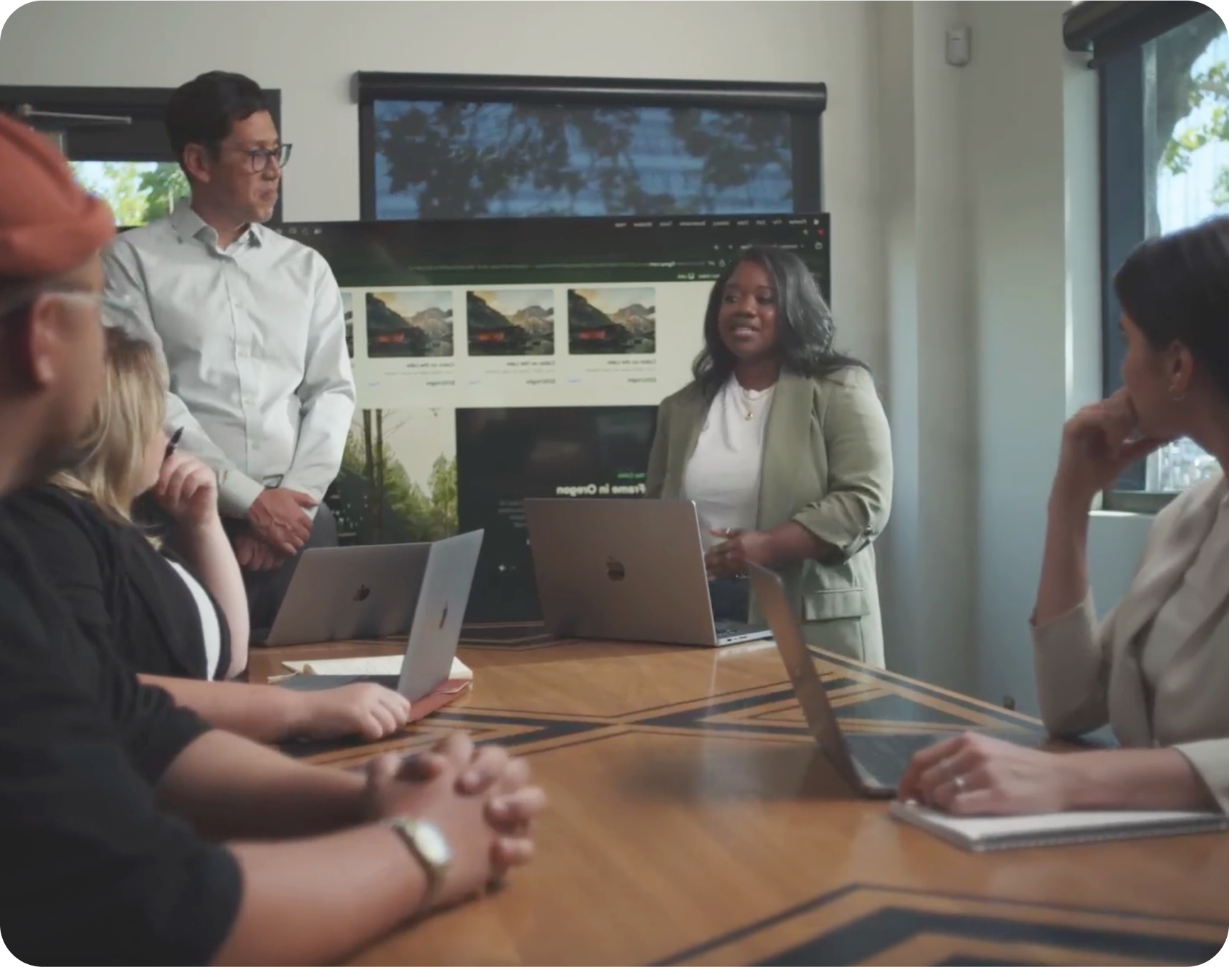 A group of people are sitting around a table with laptops.