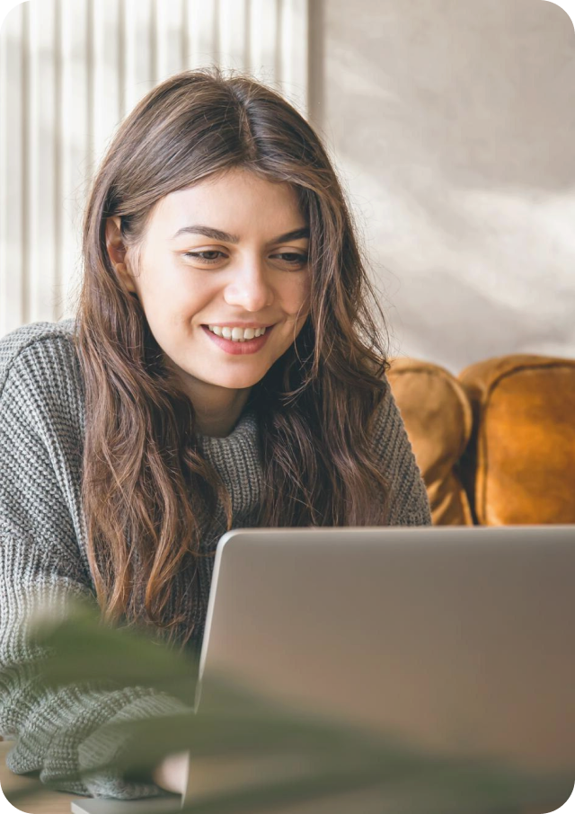 A woman is sitting on a couch using a laptop computer.