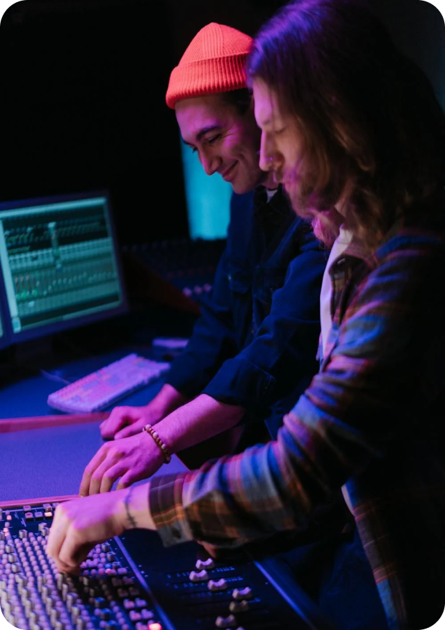Two men are working on a computer in a dark room.
