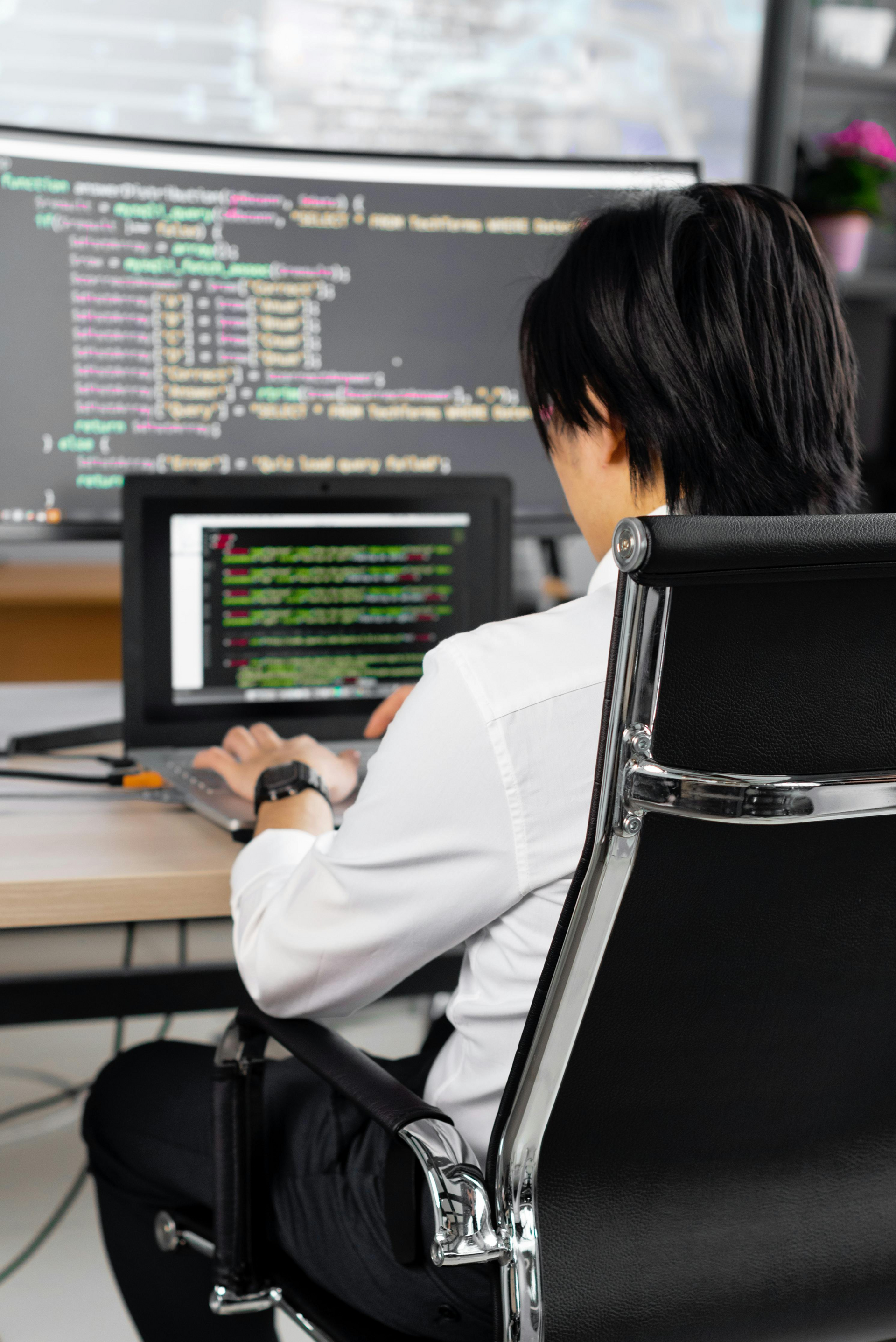 A woman is sitting at a desk using a laptop computer.