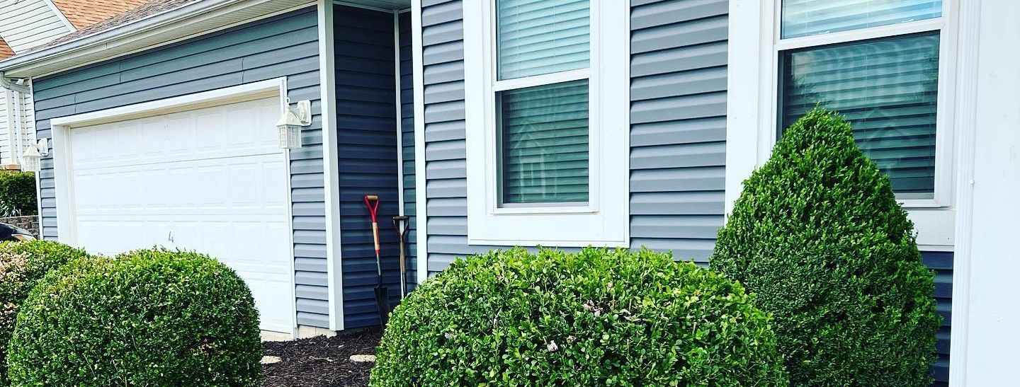 A house with a garage and a bunch of bushes in front of it.