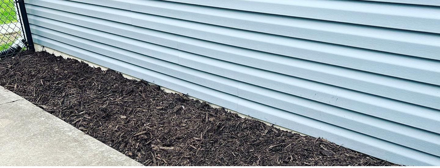 A close up of a blue siding on a house next to a sidewalk.