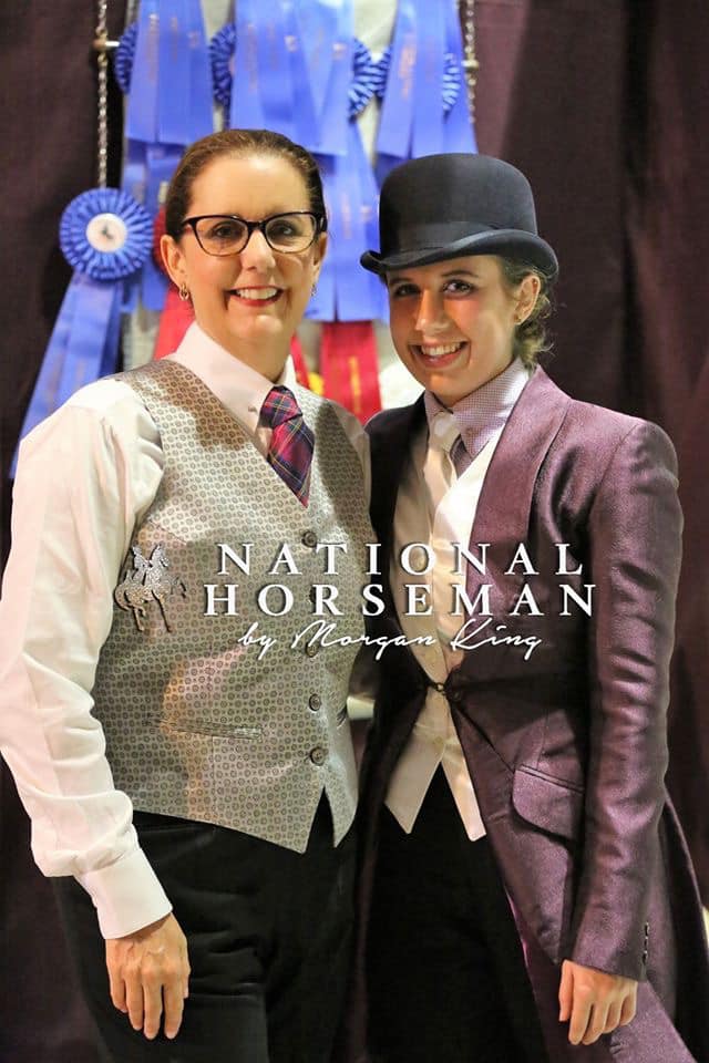 photo of a woman and her daughter dressed in saddle seat riding apparel in front of blue ribbons at a horse show