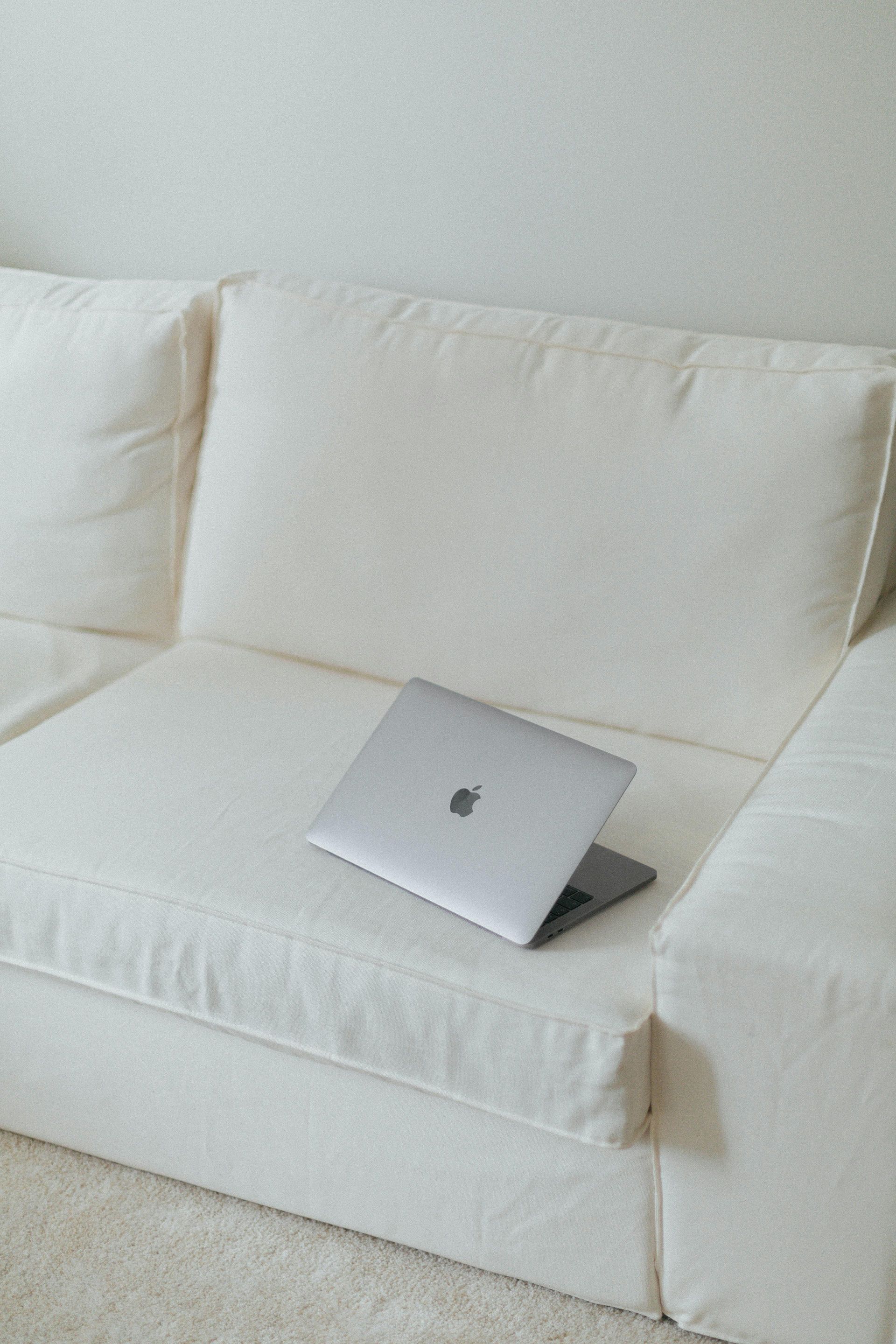 Silver laptop on a white couch in a bright room