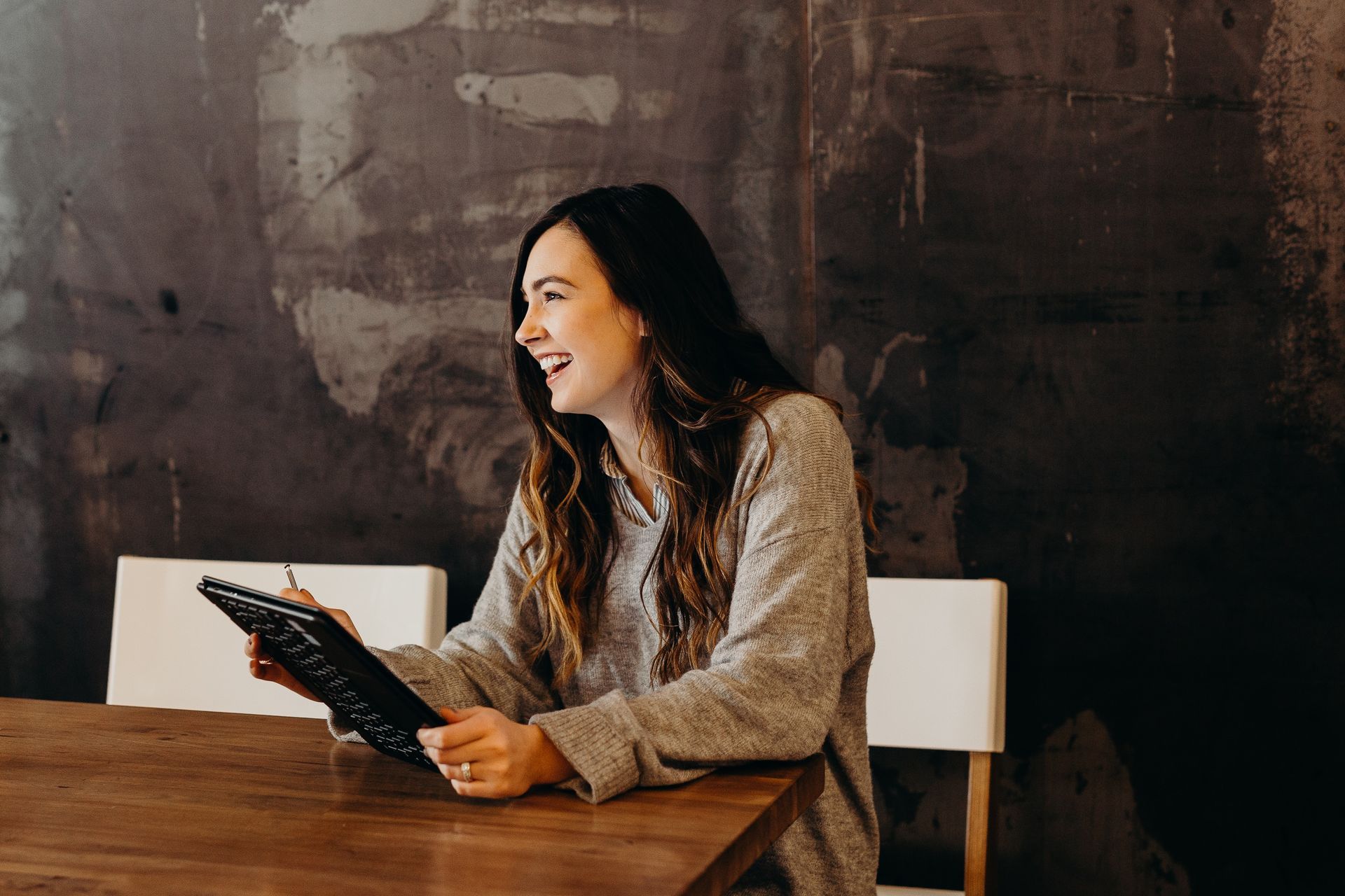 A woman is sitting at a table using a tablet computer.