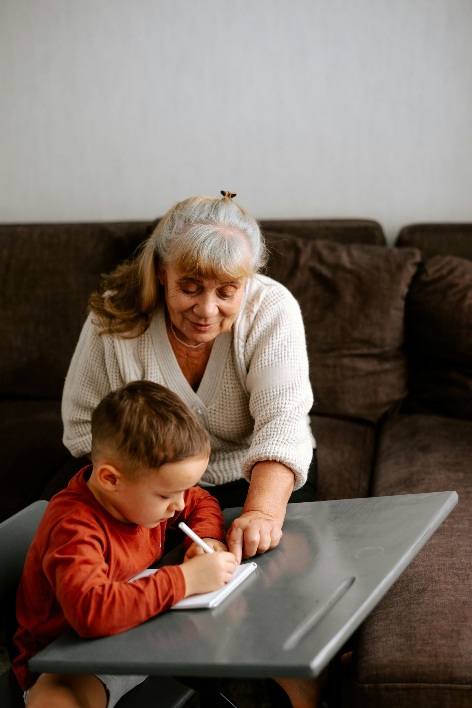 An elderly woman is helping a young boy with his homework.