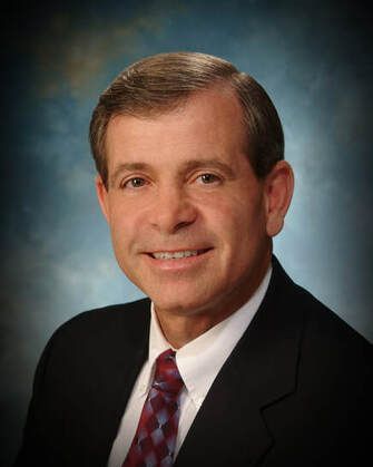 A man in a suit and tie is smiling for the camera.