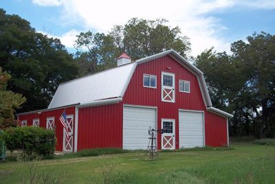 Red barn with white doors, windows, and roof against a blue sky.