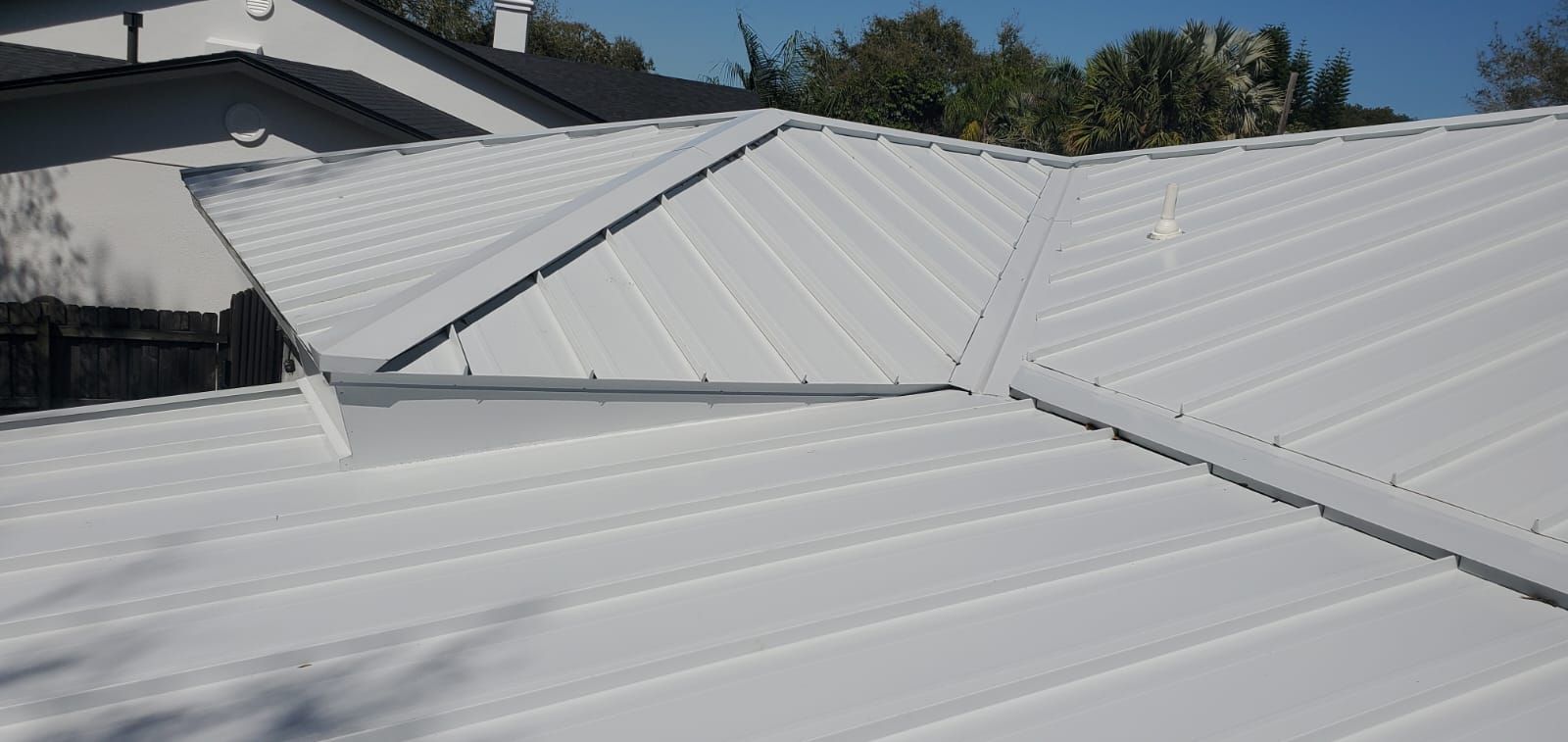 White metal roof with several angled sections, against a blue sky.