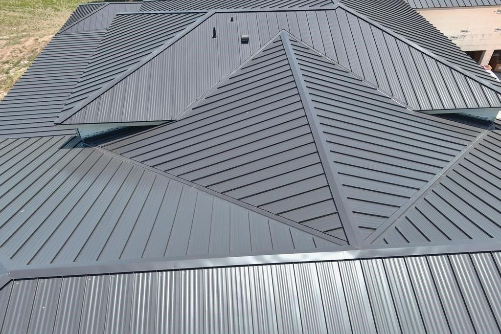 Dark metal roof with geometric patterns and ridges, viewed from above.