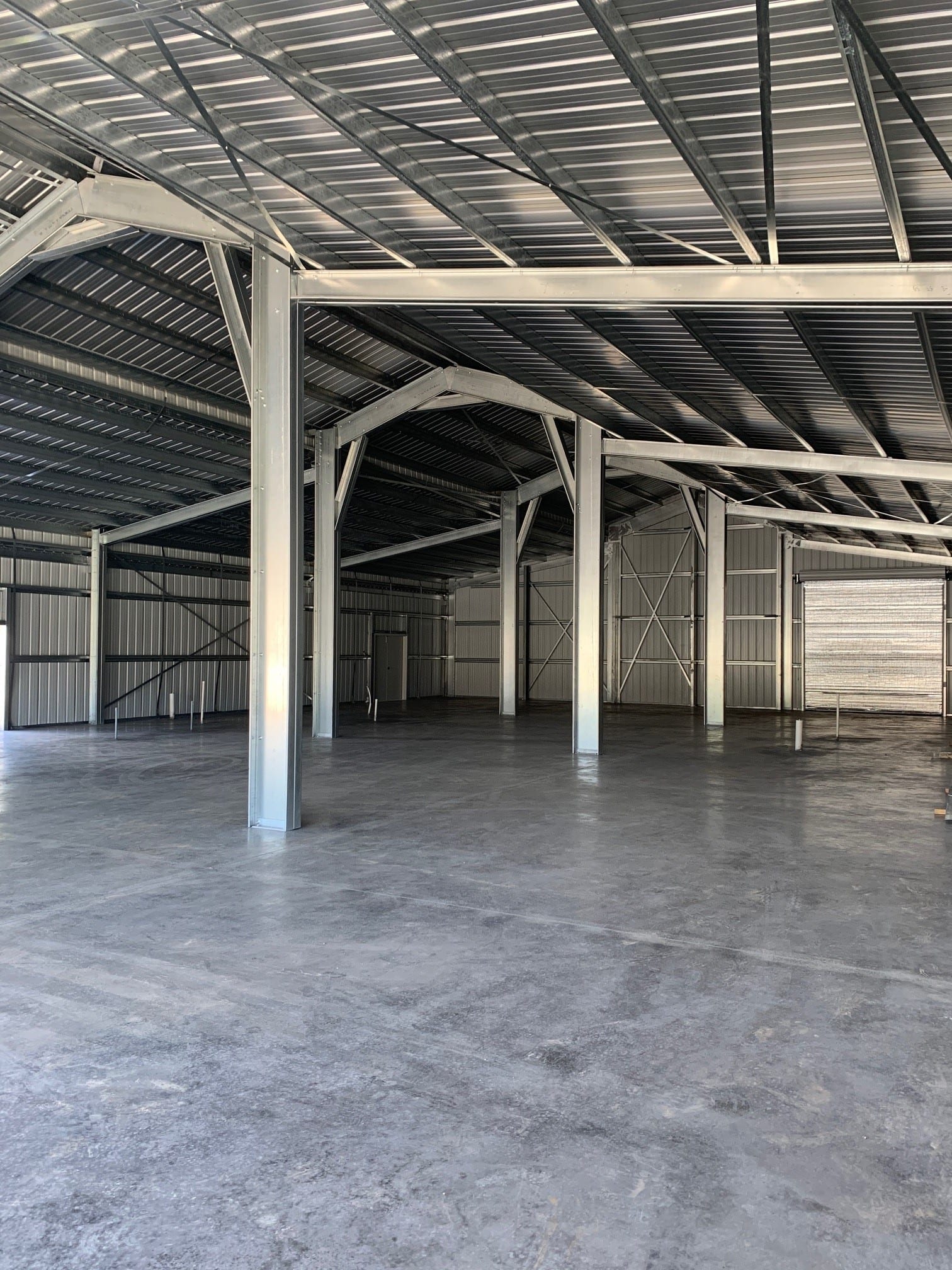 Empty metal building interior with concrete floor and exposed beams.