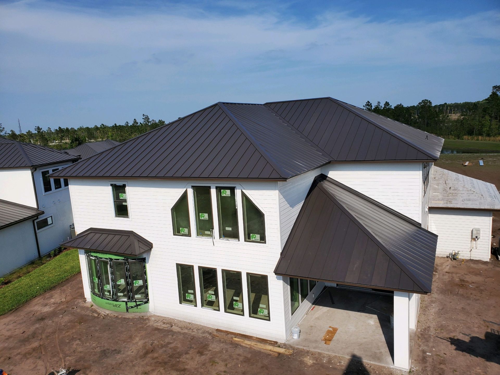 White house with dark gray roof, large windows, under construction, outdoors.