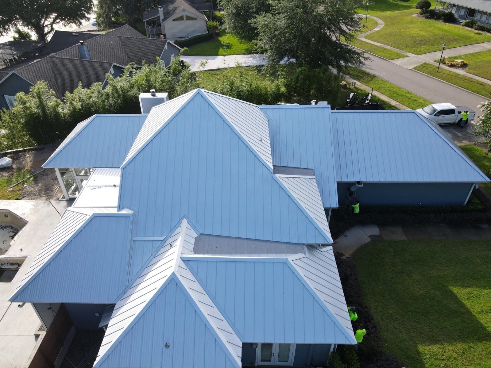 Aerial view of a house with a light blue metal roof.