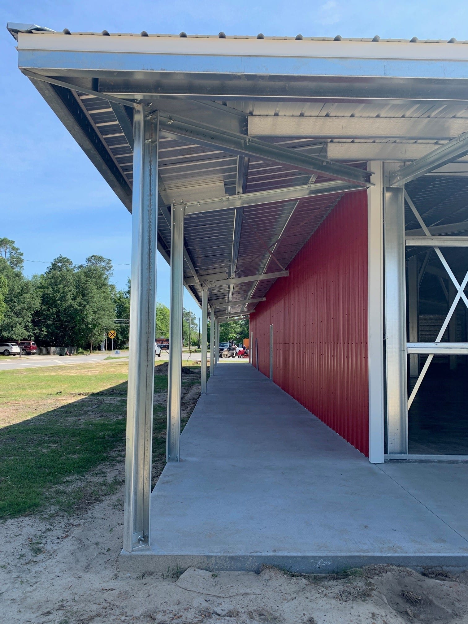 Red building with a metal overhang and concrete walkway on a sunny day.