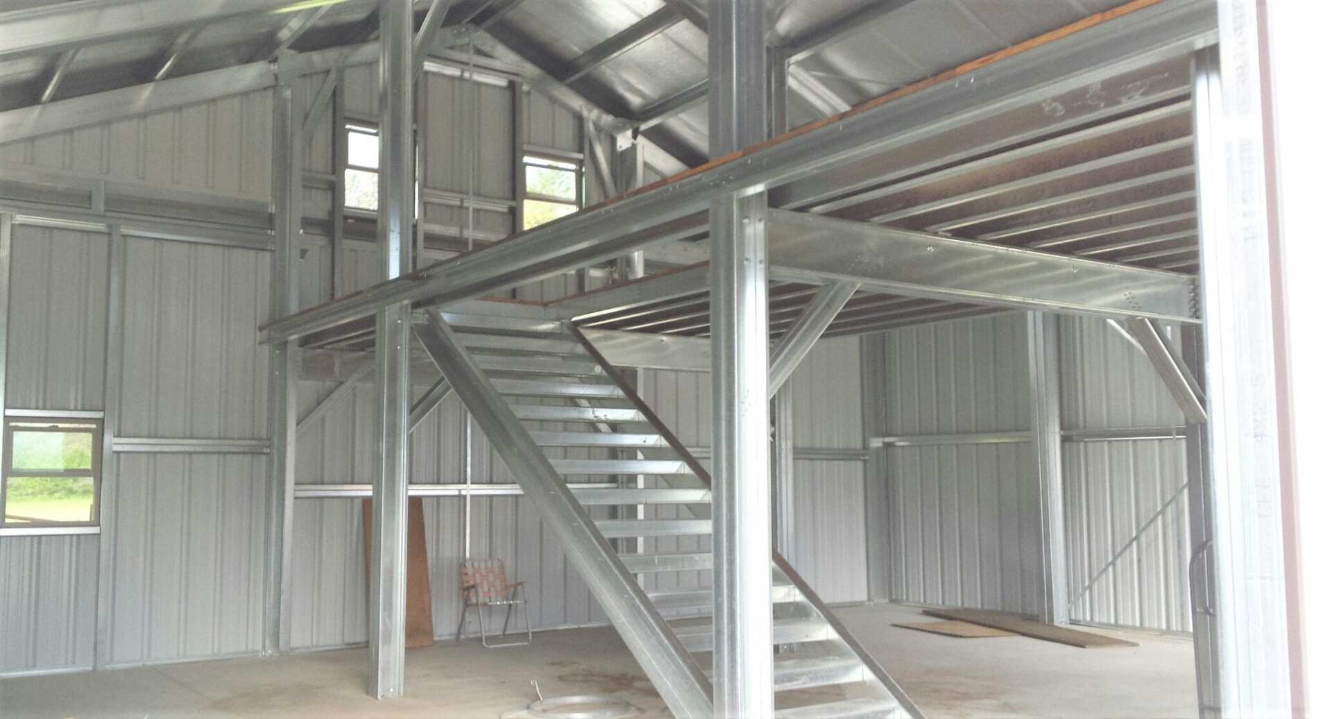 Interior of a metal building with a metal staircase leading to a loft.