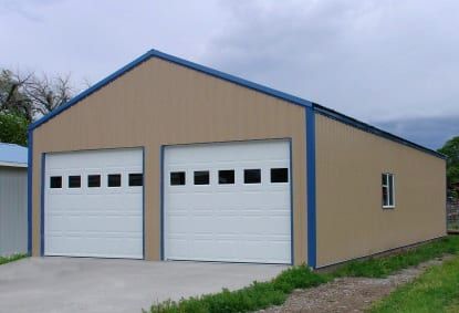Tan metal garage with two white garage doors, blue trim, and a small window.