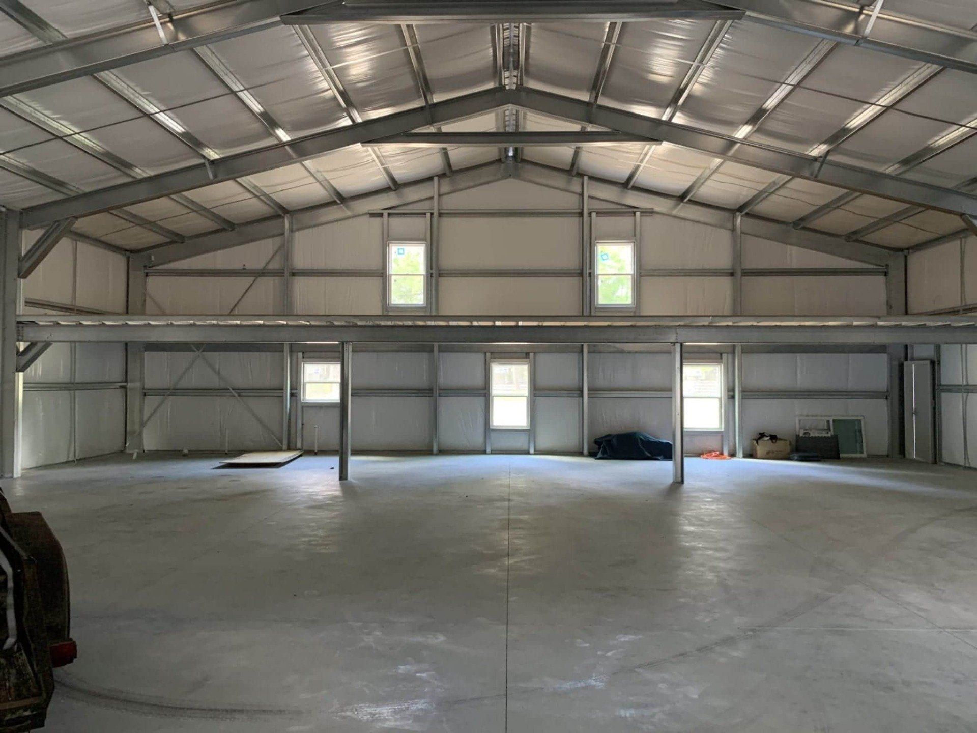 Interior view of an empty metal building with a concrete floor, and windows.