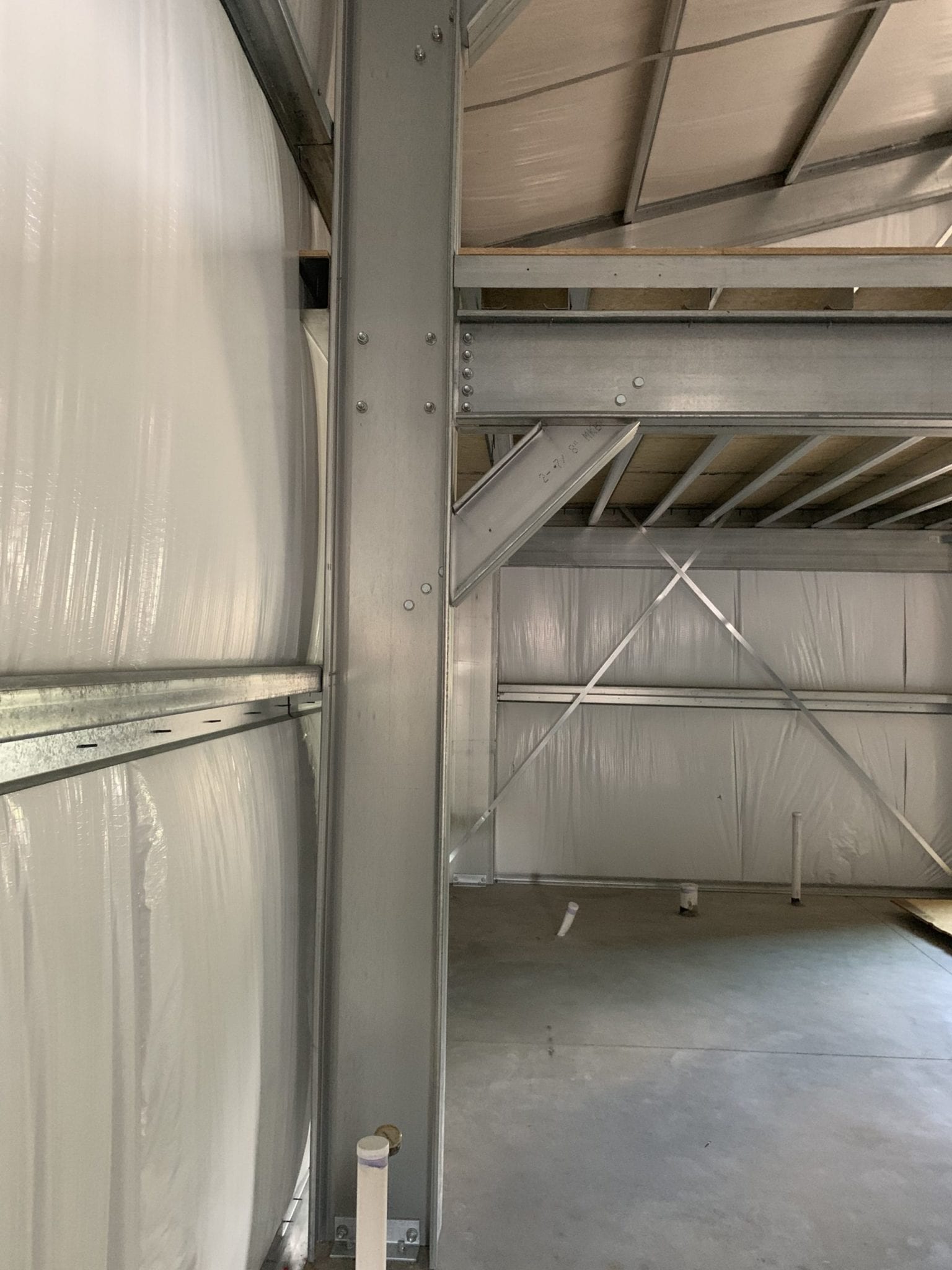 Steel support beam in an industrial building with metal siding and a partial second floor.