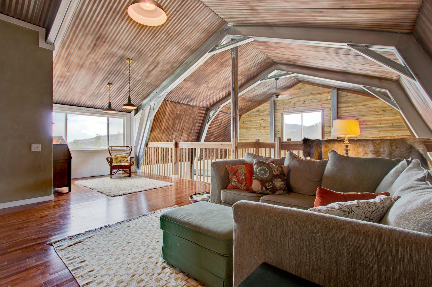 Living room with vaulted, wooden ceiling; sofa, rug, and ottoman.