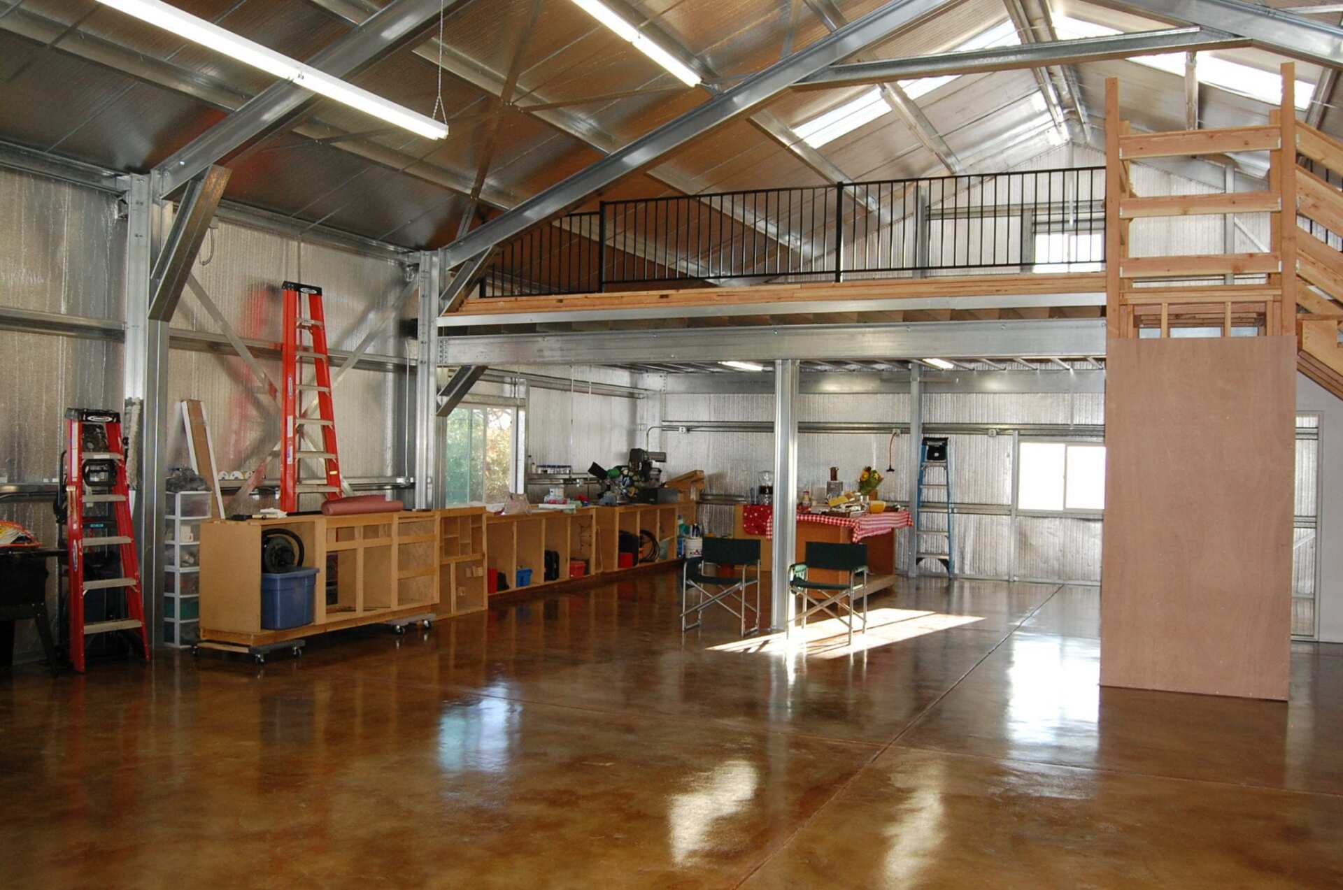 Large, open workshop with concrete floor, a metal frame, and a mezzanine level.