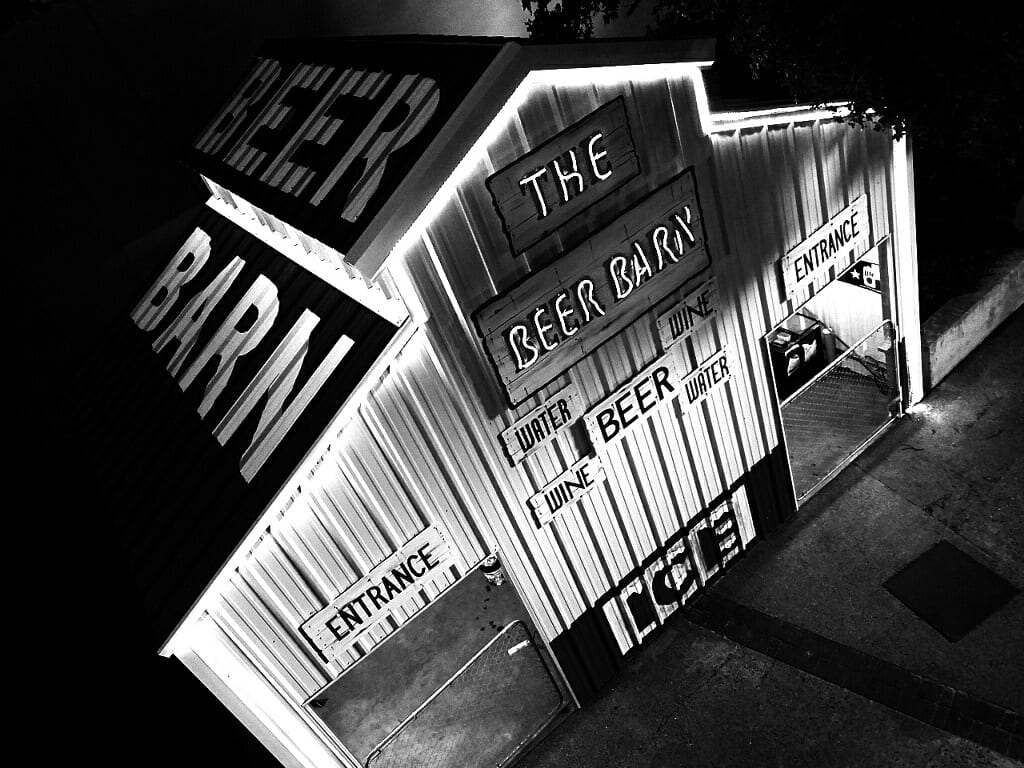 The Beer Barn at night, illuminated signs, entrance and ice signs are visible.
