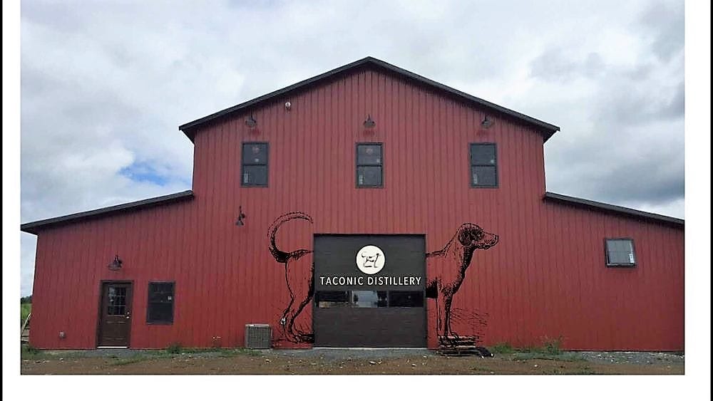Red barn with a metal camel sculpture and sign for The Milk & Honey.