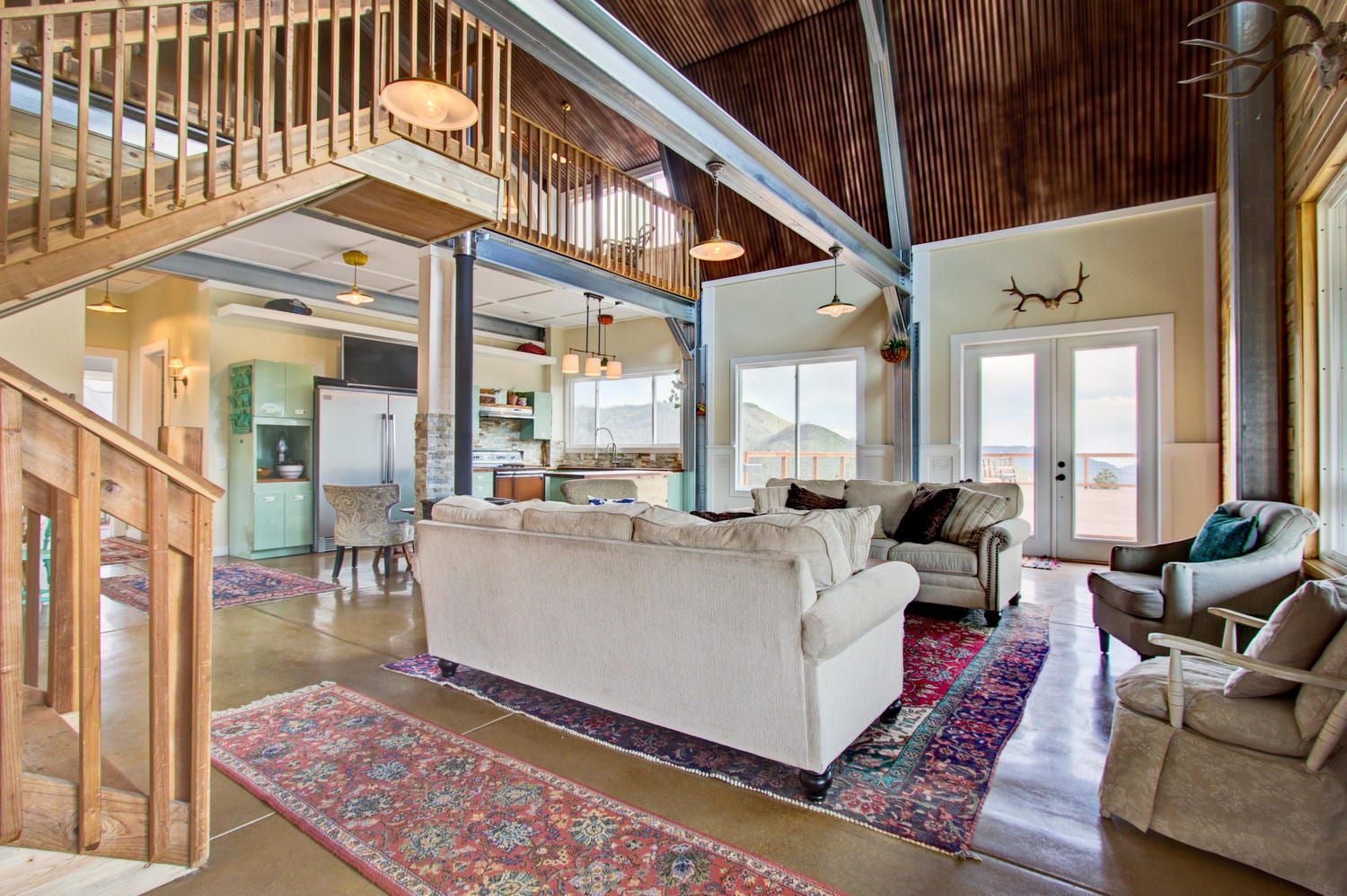 Spacious living room with a view. Features a loft, couches, rug, and natural light.
