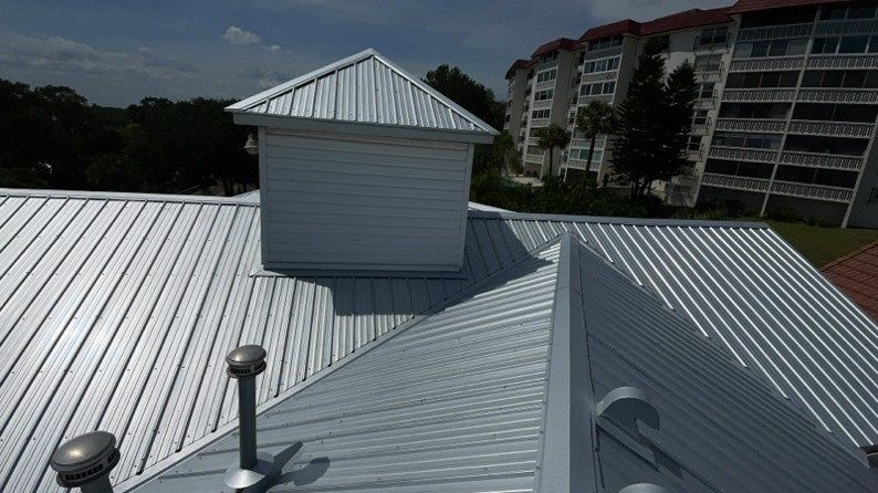 Metallic roof with a small square structure on top.