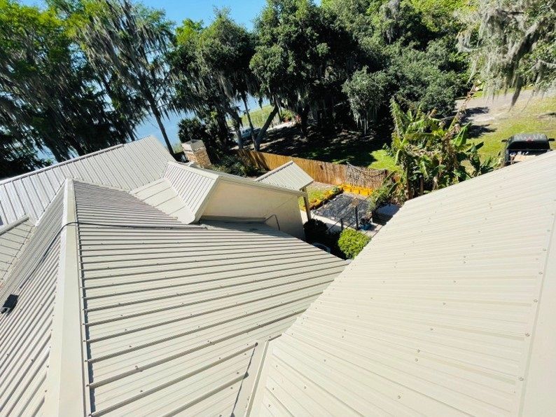 Metal roof of a house overlooking a lake and trees.