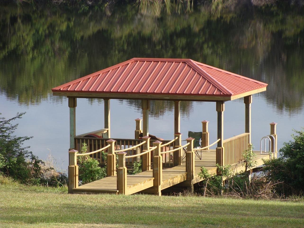 Gazebo on a wooden dock with a red roof over a calm body of water.