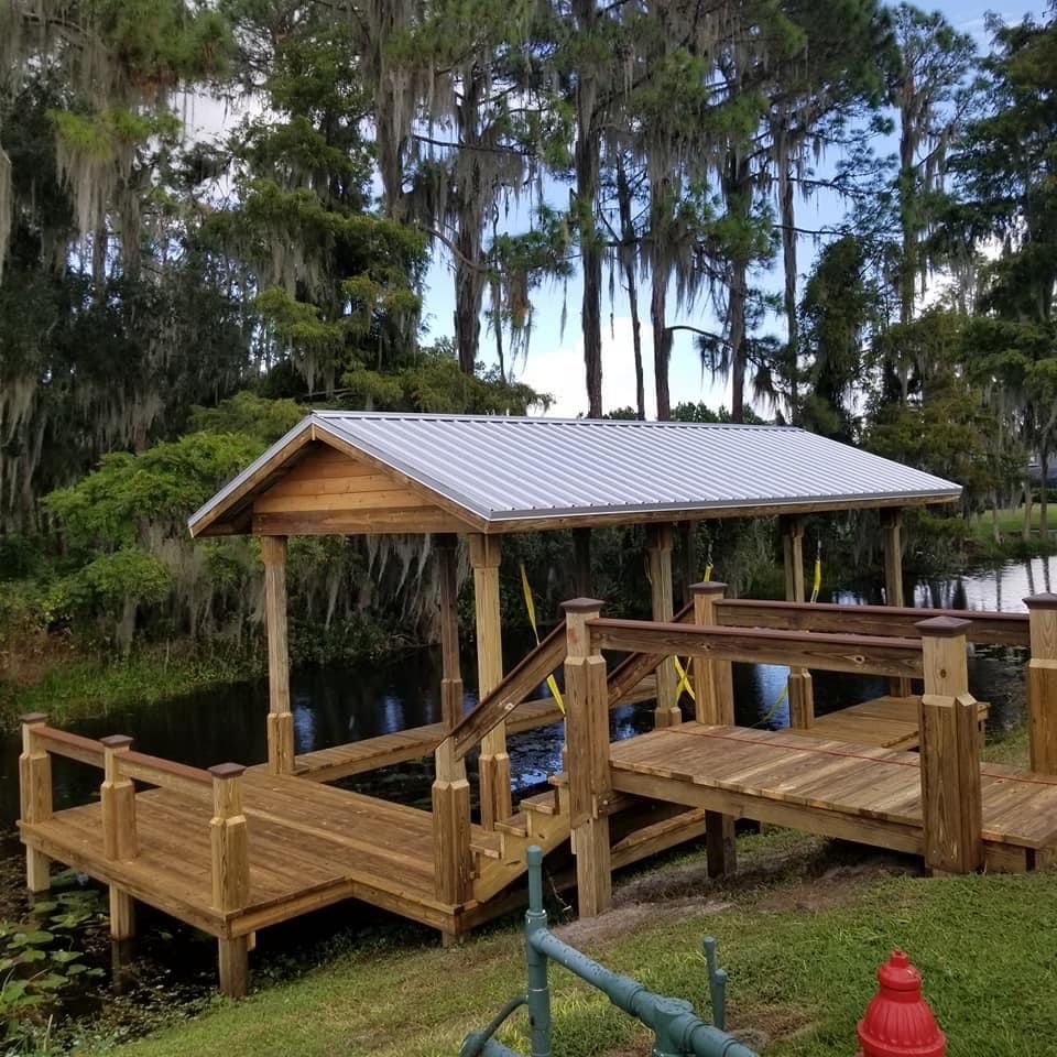 Wooden dock with a covered boat slip and a bridge, set on a lake.